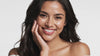Young woman with glowing skin gently touching her face and smiling